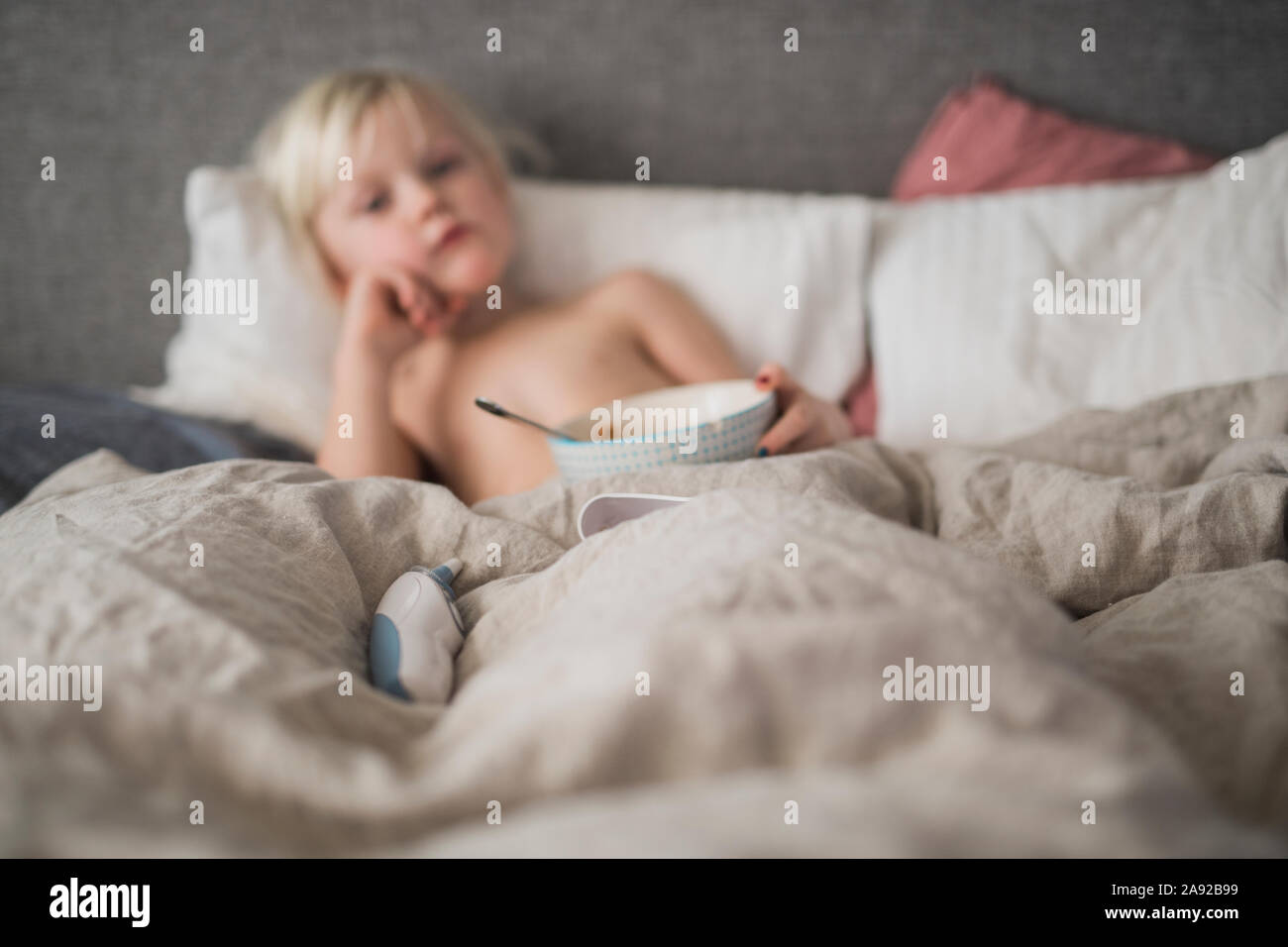 Termometro digitale sul letto, ragazzo sullo sfondo Foto Stock