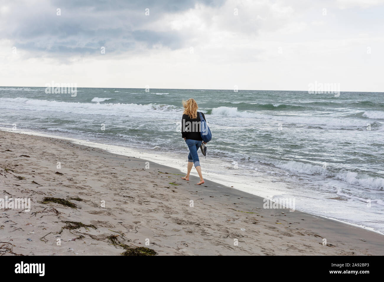 Donna che cammina sulla spiaggia Foto Stock