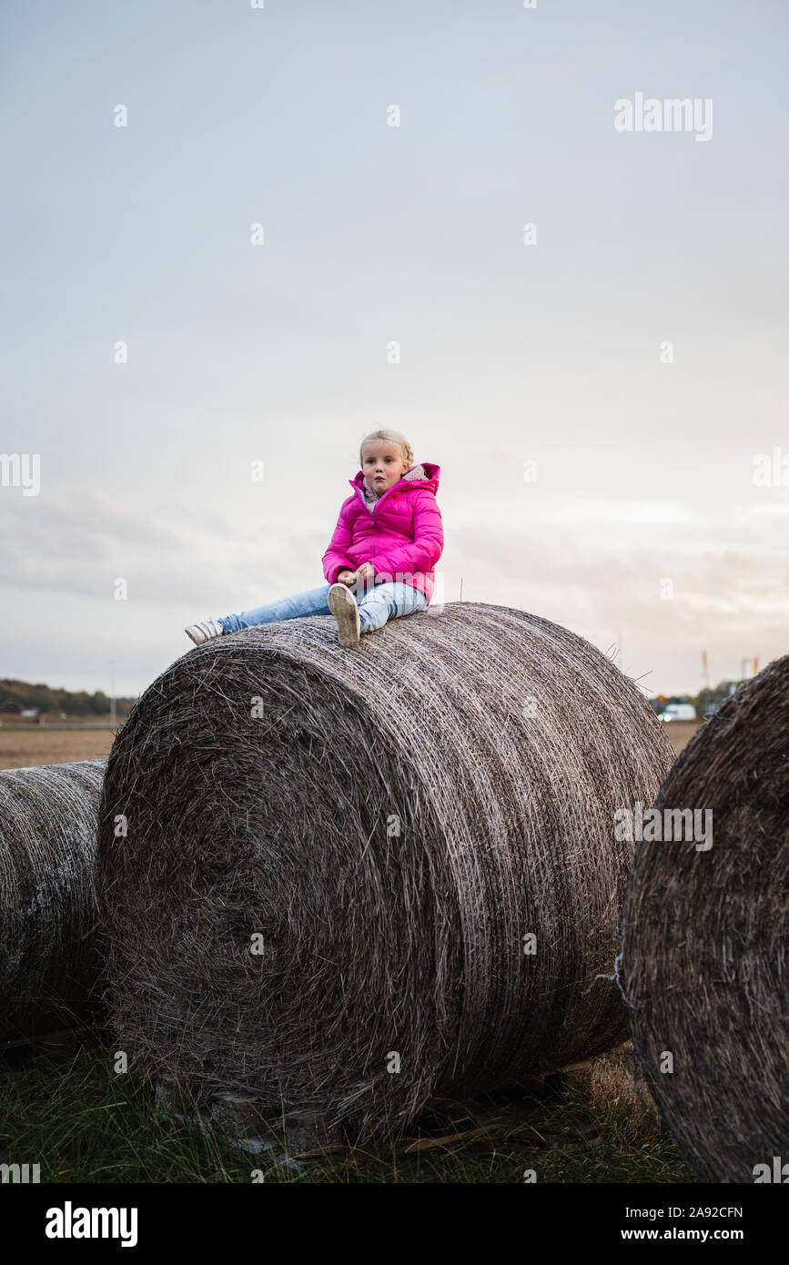 Ragazza seduta sulla balla di fieno Foto Stock