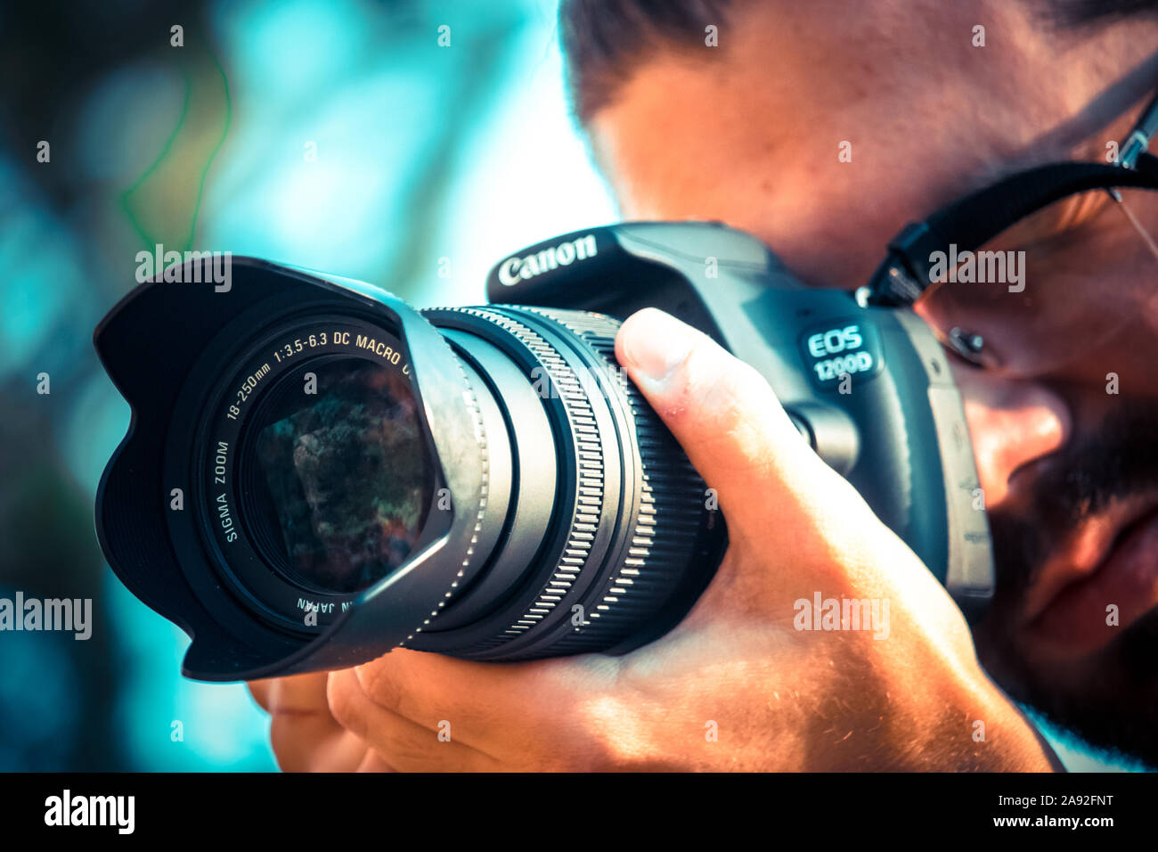 Fotografo tenendo un Canon 1200d con fotocamera Sigma 18-250 lens.guardando  attraverso il mirino per scattare una foto Foto stock - Alamy
