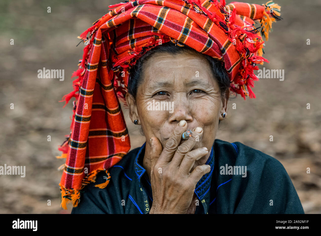 Donna birmana che indossa una testa tradizionale coprendo e fumando una sigaretta; Yawngshwe, Shan state, Myanmar Foto Stock