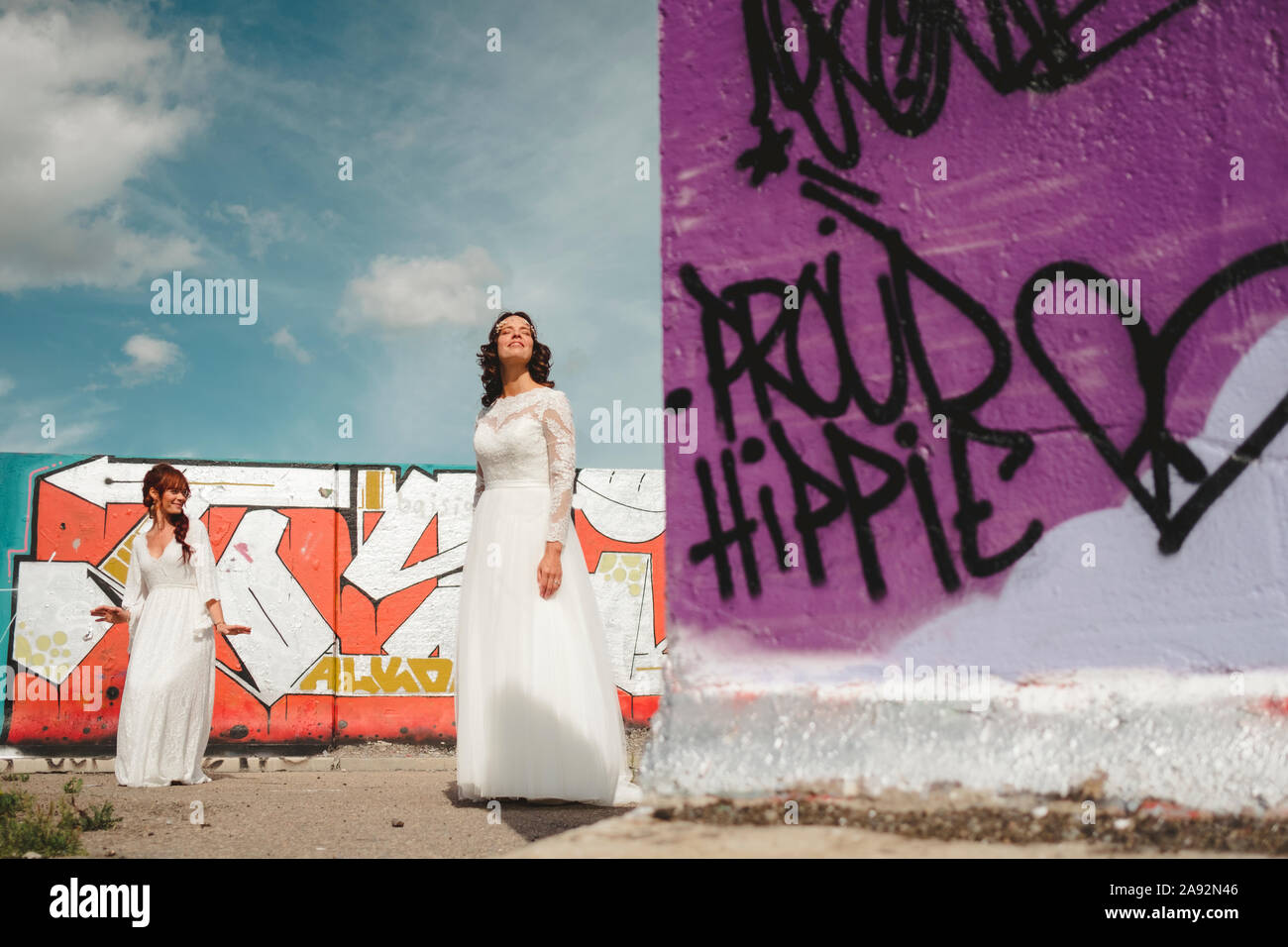 Spose in piedi vicino a muro con graffiti Foto Stock