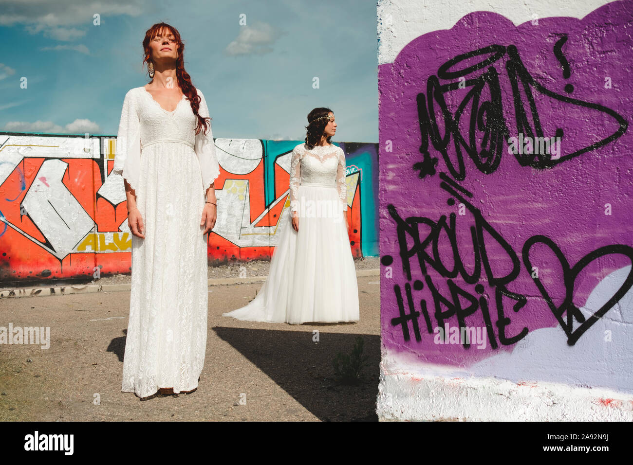 Spose in piedi vicino a muro con graffiti Foto Stock