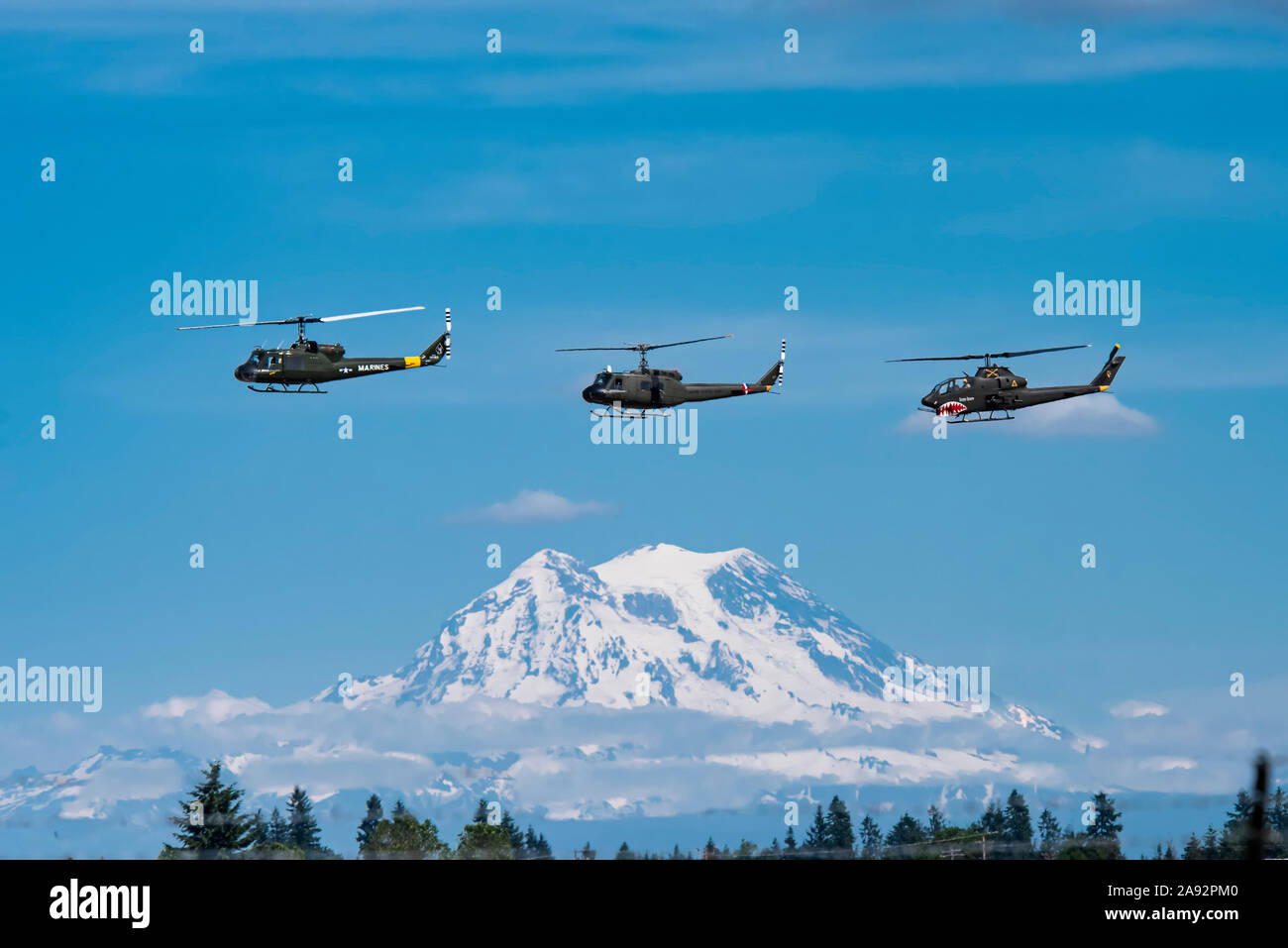 Un paio di UH-1 Huey Elicotteri e un AH-1 Cobra volare in formazione con Mount Rainier sullo sfondo, 2019 Olympic Air Show, Aeroporto Olimpico Foto Stock