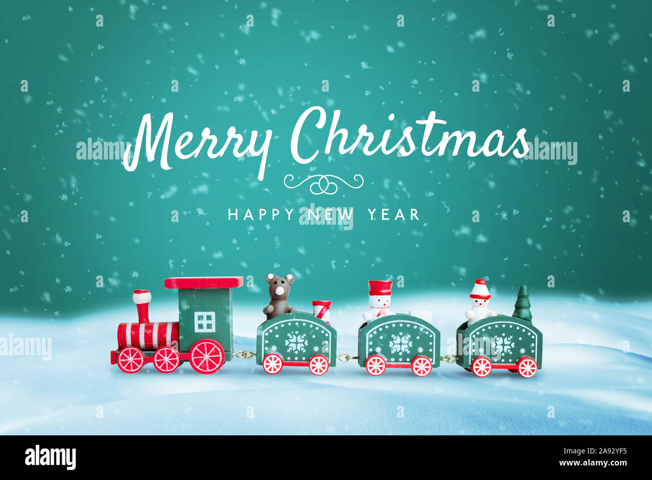 Buon Natale e Felice Anno Nuovo biglietto di auguri con il simpatico  giocattolo treno sulla neve con sfondo verde e un sacco di fiocchi di neve  Foto stock - Alamy