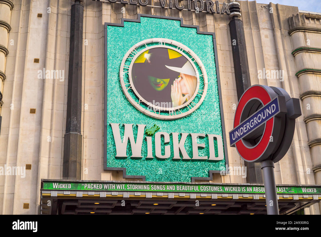 Vista di Apollo Victoria Theatre London (di fronte alla stazione di Victoria) pubblicità hit musical produzione malvagi. La metropolitana di Londra roundel in primo piano. Foto Stock