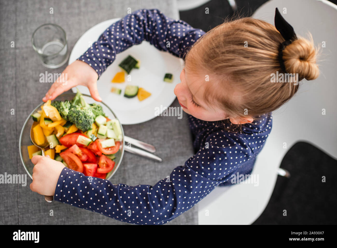 Ragazza insalata mettendo su piastra Foto Stock