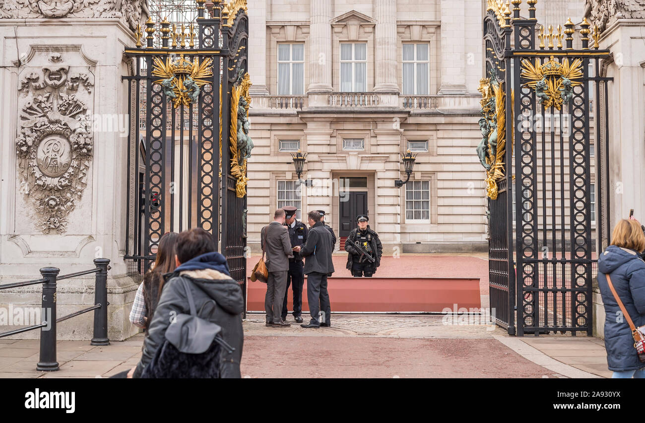 Guardando attraverso le porte aperte di fronte a Buckingham Palace, nel centro di Londra, Regno Unito. Polizia armata sulla guardia di controllo della sicurezza dei visitatori. Guardia famiglia reale. Foto Stock