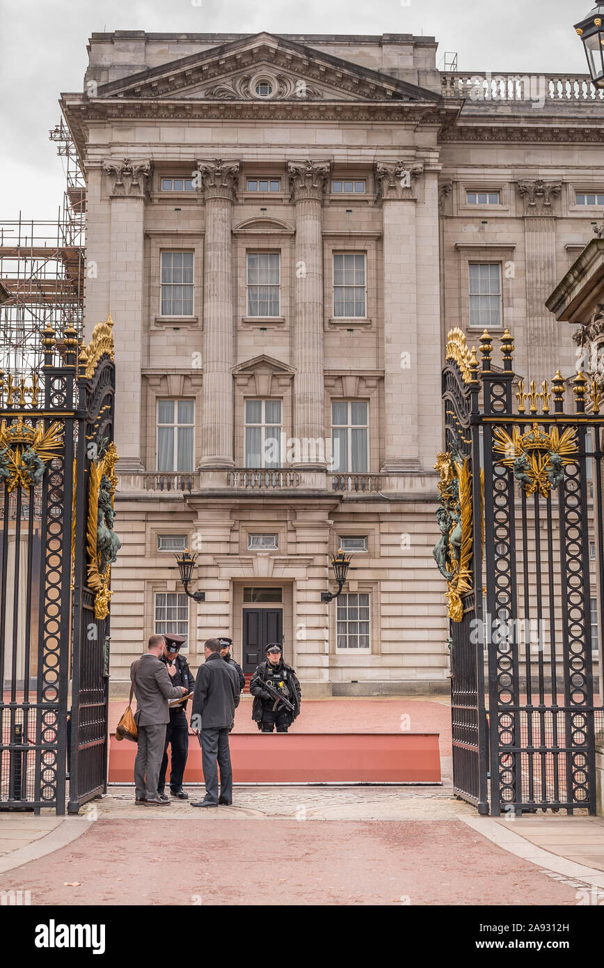 Guardando attraverso le porte aperte di fronte a Buckingham Palace, nel centro di Londra, Regno Unito. Polizia armata sulla guardia di controllo della sicurezza dei visitatori. Guardia famiglia reale. Foto Stock