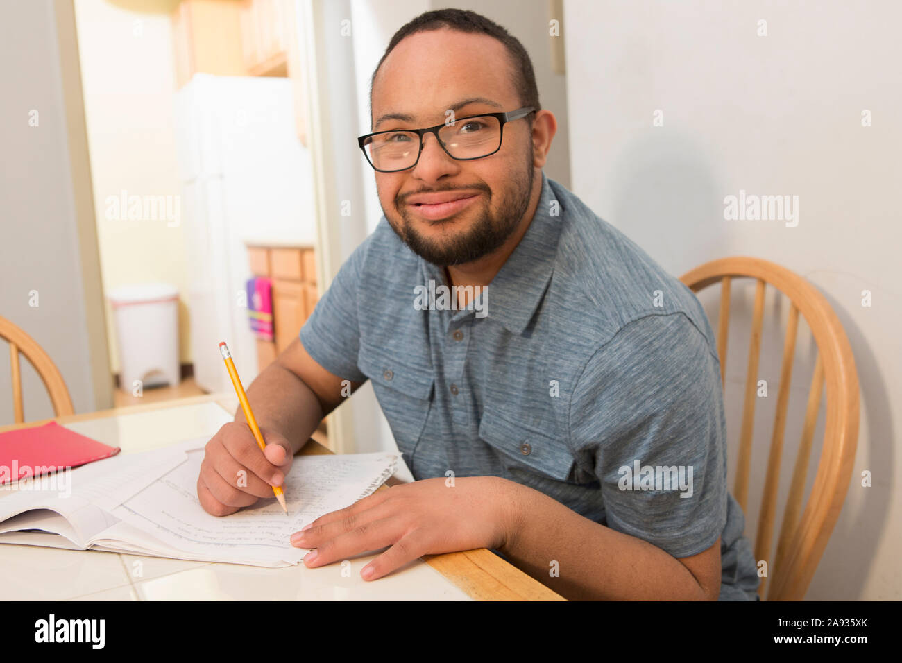 Felice uomo afroamericano con la sindrome di Down facendo il lavoro di ufficio a. casa Foto Stock