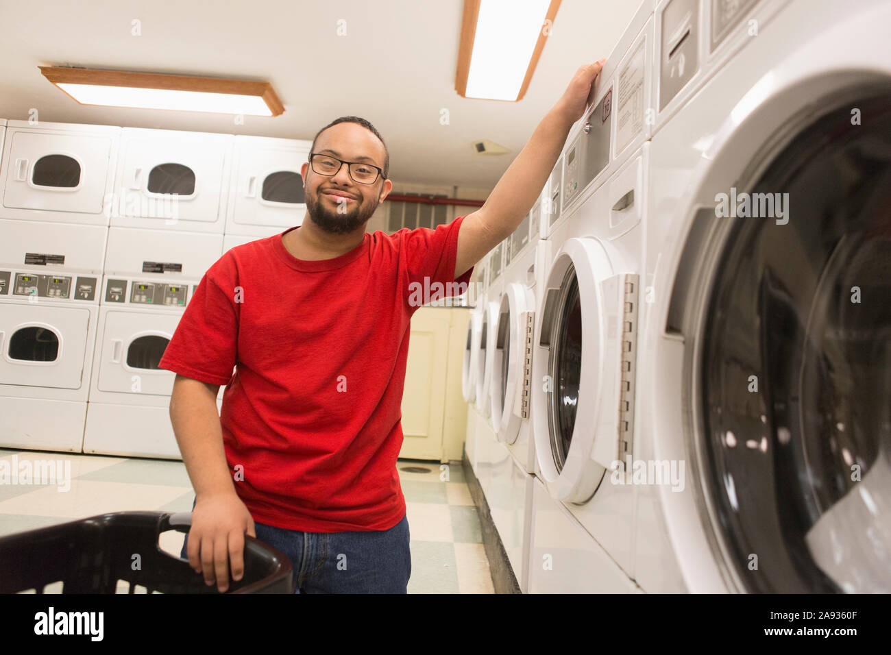 Felice uomo afroamericano con la sindrome di Down facendo lavanderia dentro ripostiglio Foto Stock