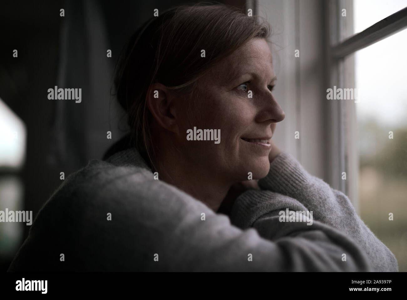 Donna che guarda attraverso la finestra Foto Stock