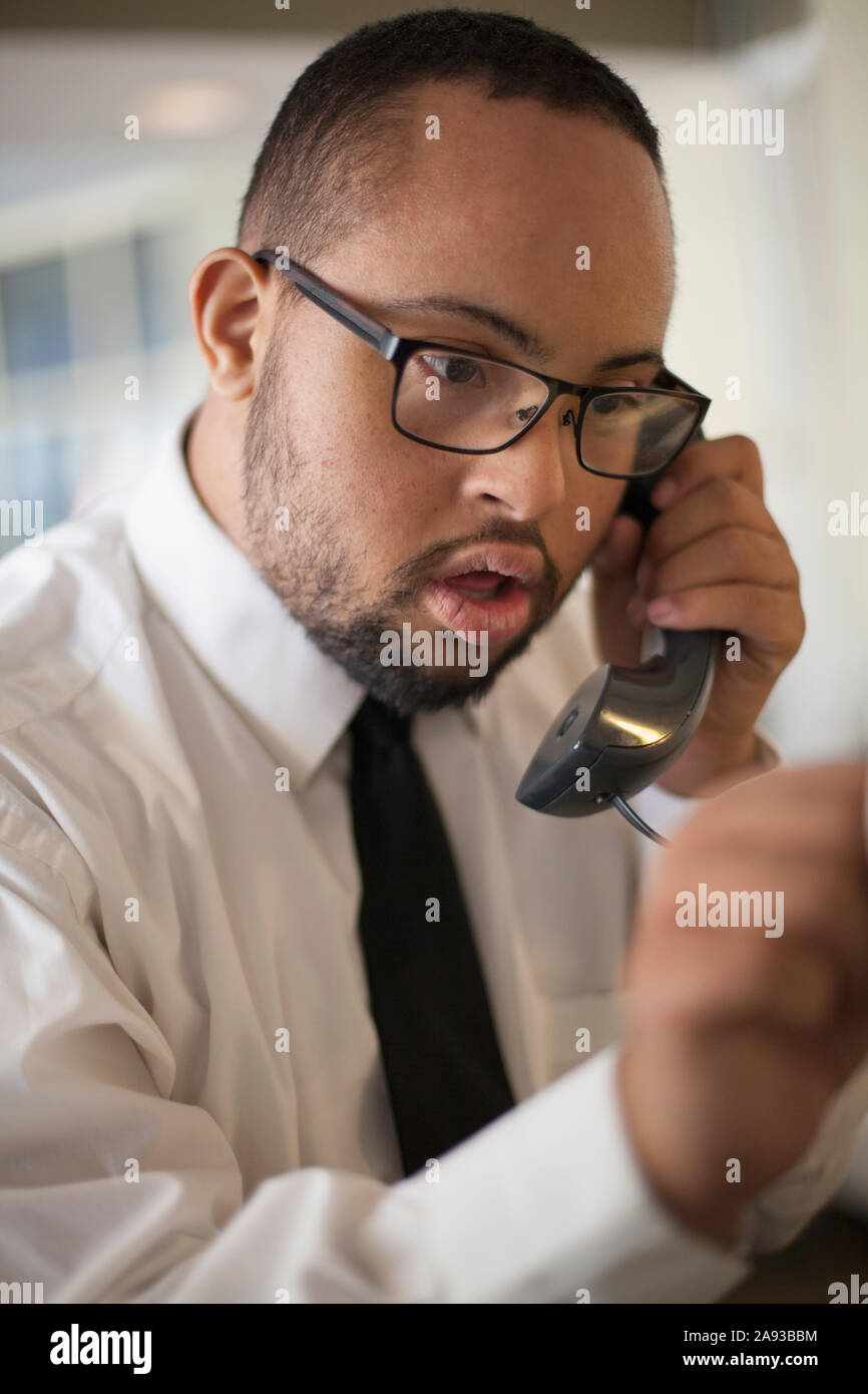 L'uomo afroamericano con la sindrome di Down come un cameriere che prende prenotazioni in ristorante Foto Stock