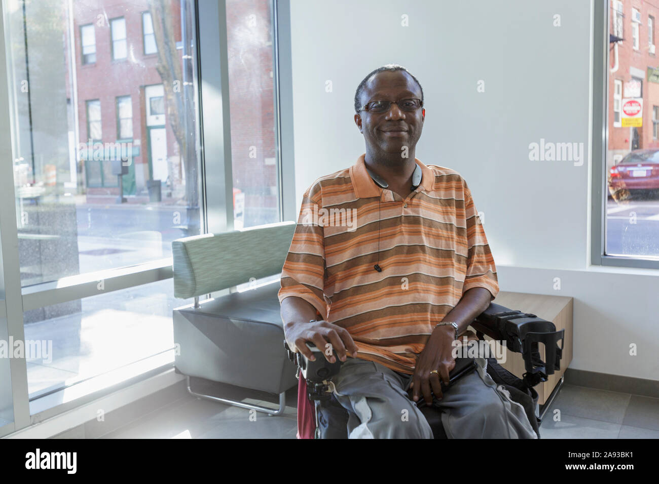 Uomo con sindrome di Guillain-barre su sedia a rotelle di fronte al finestra dell'appartamento Foto Stock