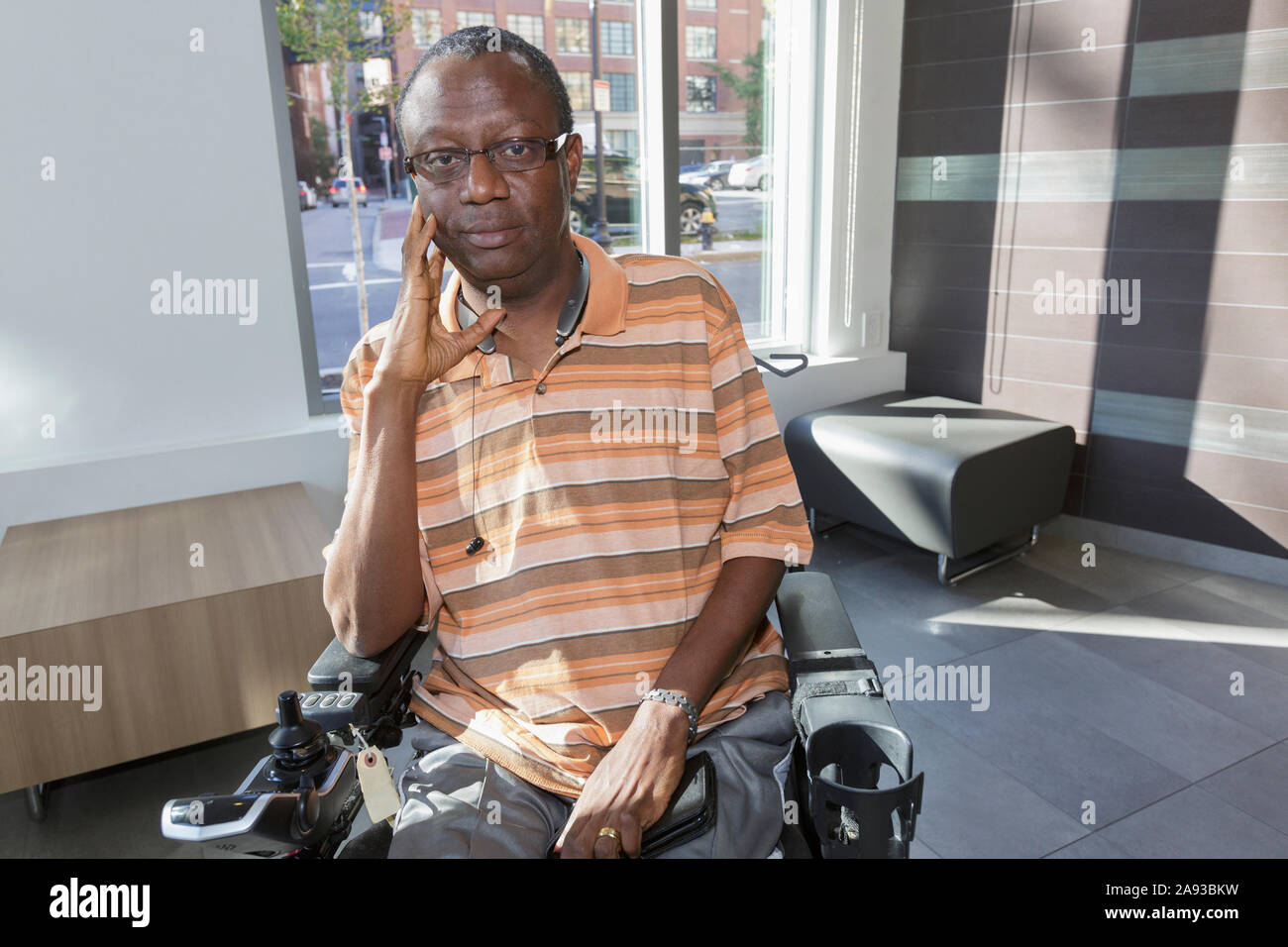 Uomo con sindrome di Guillain-barre su sedia a rotelle di fronte al finestra dell'appartamento Foto Stock