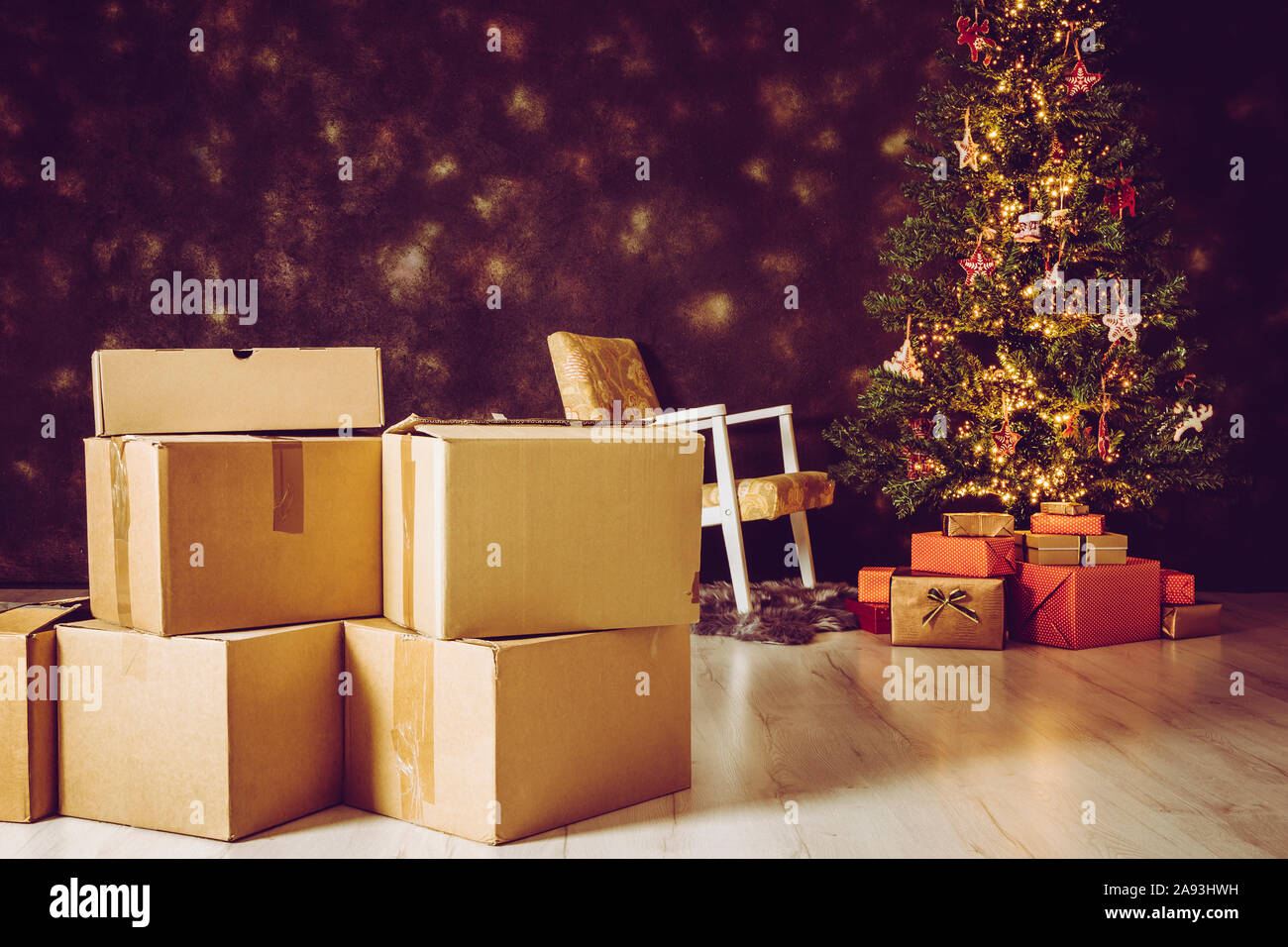 In Movimento per la casa nuova per il concetto di Natale. Focus sulla delocalizzazione di cartone scatole e albero di Natale decorato con presenta sotto di esso sullo sfondo Foto Stock