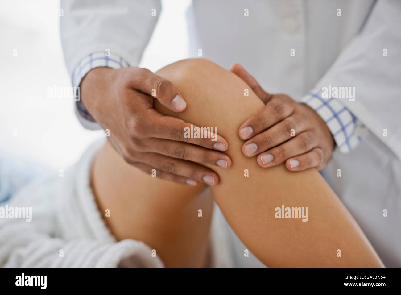 Le mani del medico esaminano il ginocchio di un paziente Foto Stock