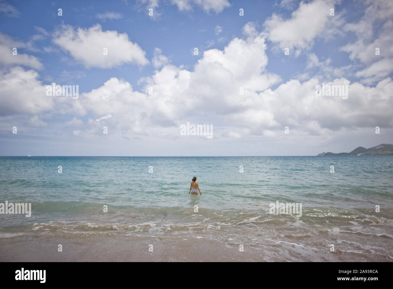Donna che cammina fuori nell'oceano su una spiaggia. Foto Stock