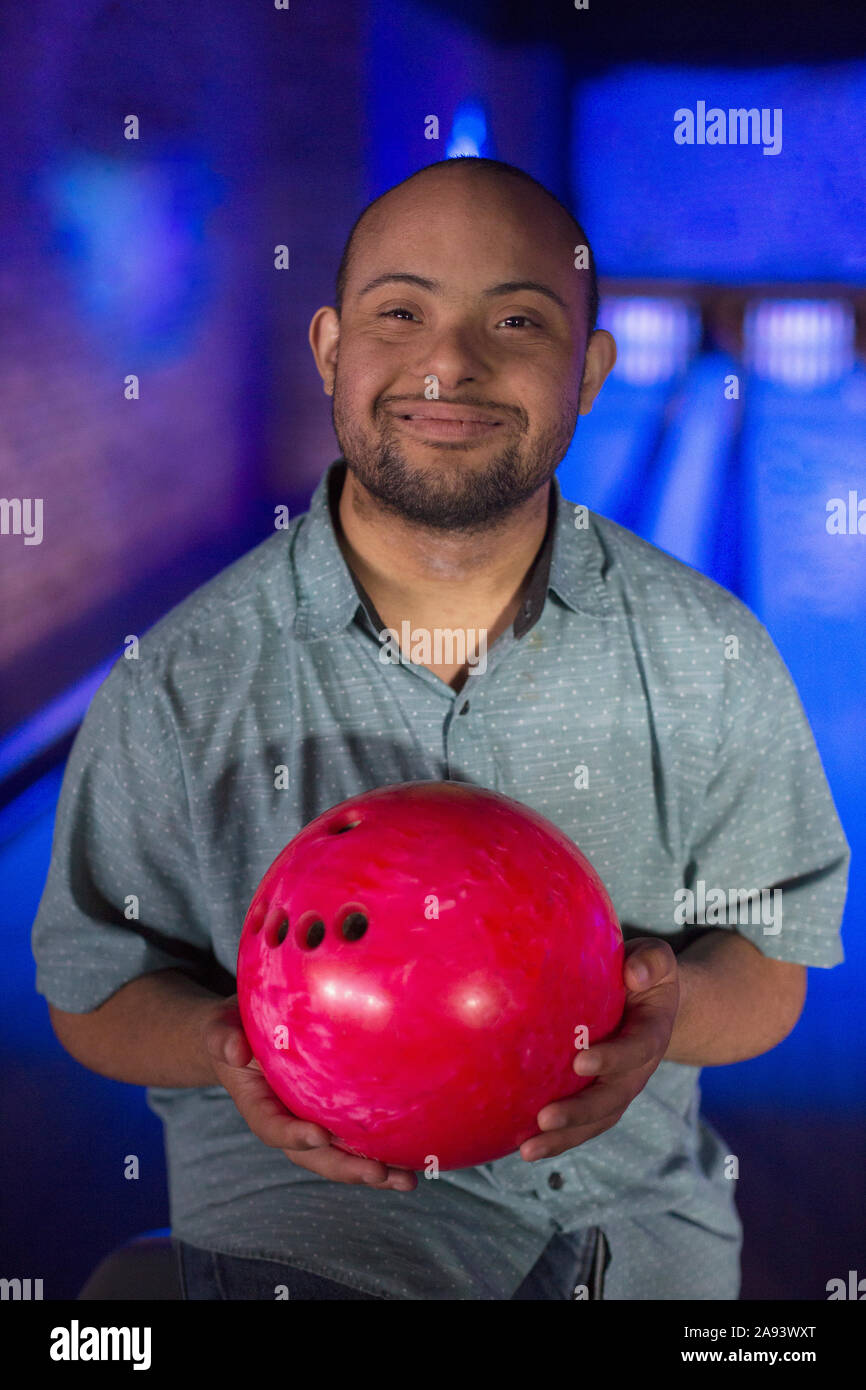 L'uomo afroamericano che ha la sindrome di Down tenendo un bowling sfera Foto Stock