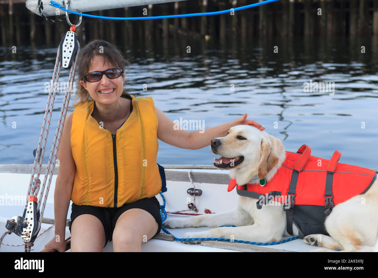 Donna con disabilità visiva seduta in barca a vela con servizio cane Foto Stock