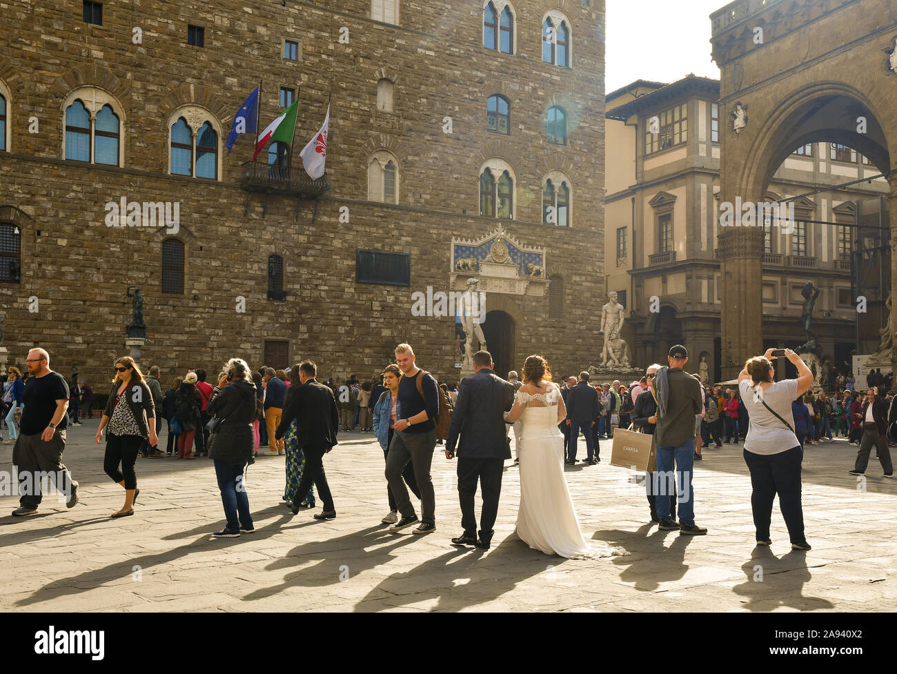 Coppia di testa verso l'ingresso di Palazzo Vecchio in Piazza della Signoria, sede del municipio di Firenze, per unirsi in matrimonio, Toscana, Italia Foto Stock