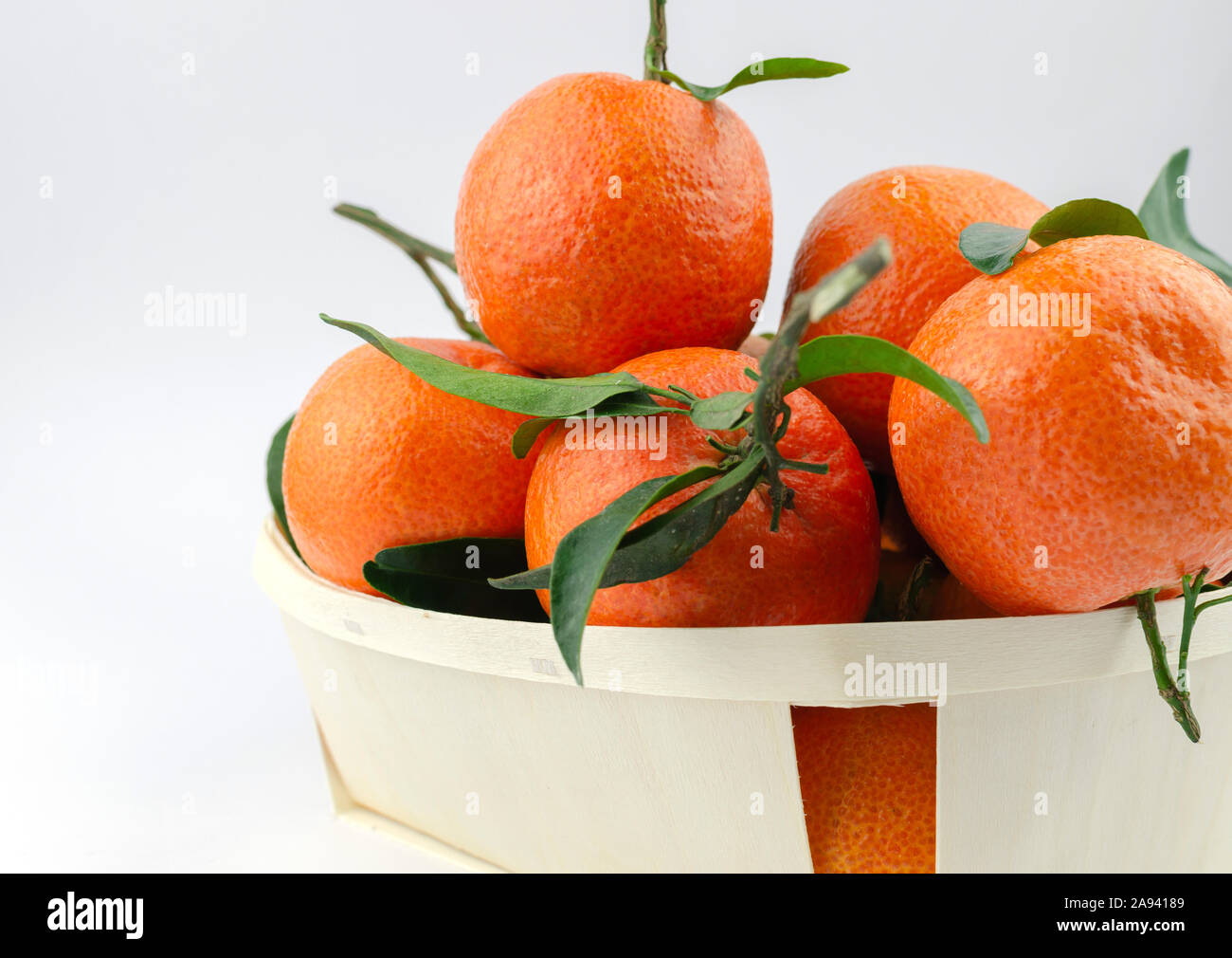 Extra dolce e succosa clementine spagnole con foglie in una cesta. Isolato su bianco. Foto Stock