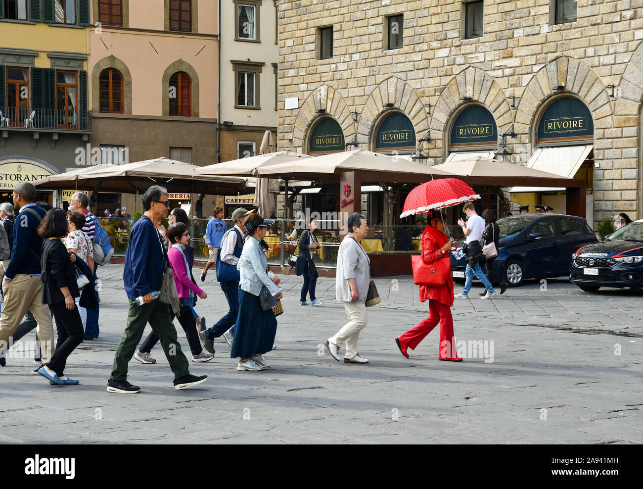 Un gruppo di turisti asiatici a seguito di una guida turistica vestito di rosso in Piazza della Signoria, Sito Patrimonio Mondiale dell'Unesco, Firenze, Toscana, Italia Foto Stock