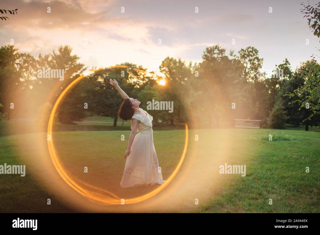 Un ballerino sorge in un anello di luce al tramonto nel parco alberato Foto Stock