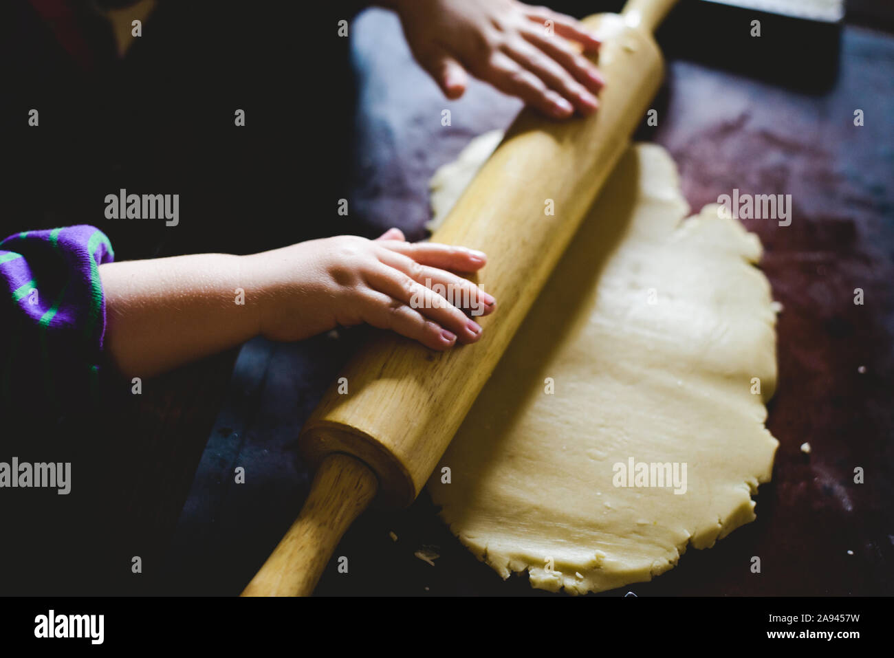 Un bambino rotola fuori qualche impasto per fare i cookie. Foto Stock