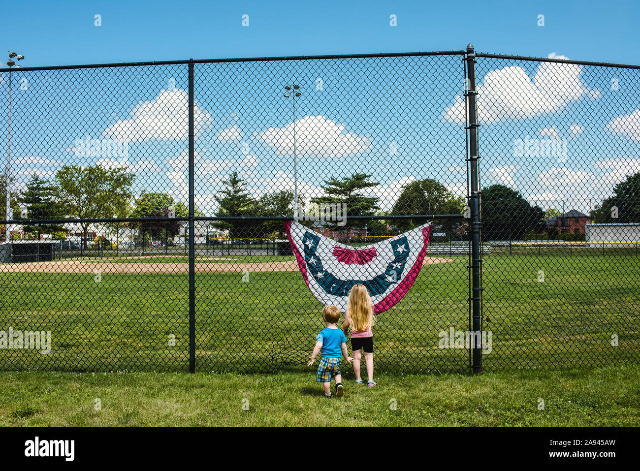 Due bambini in stand by un indicatore in un campo da baseball. Foto Stock