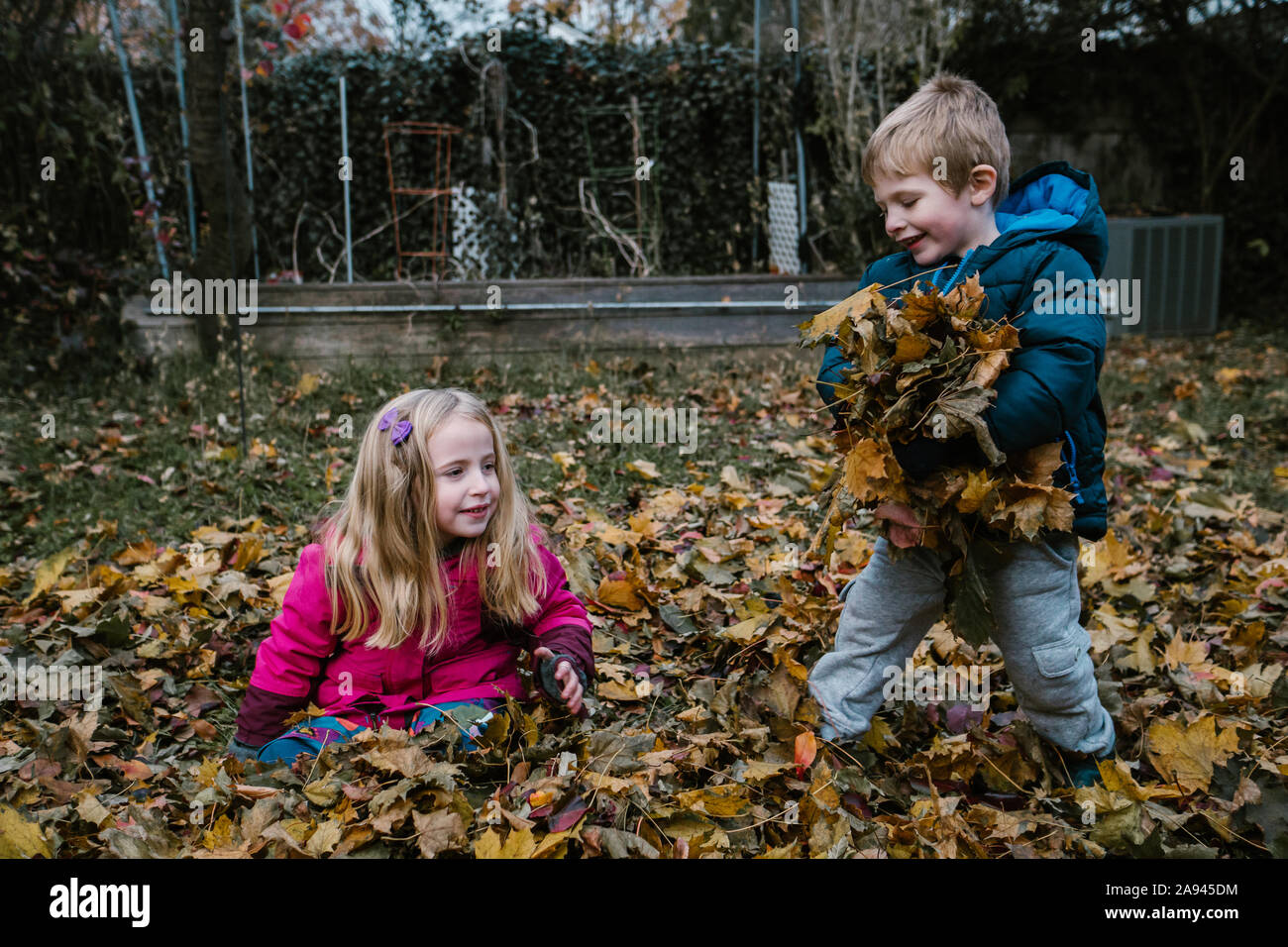 Due bambini di giocare in un mucchio di foglie. Foto Stock