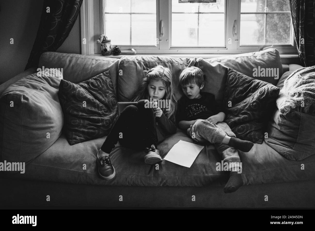 Due bambini di giocare con una compressa su un lettino. Foto Stock