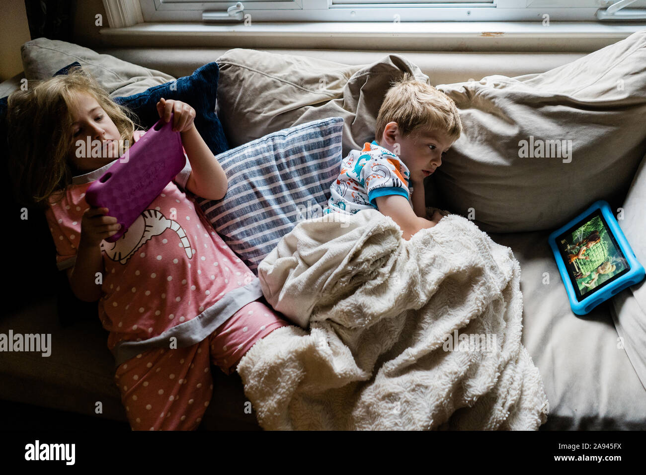 Due bambini giacciono su un lettino e guardare le compresse. Foto Stock