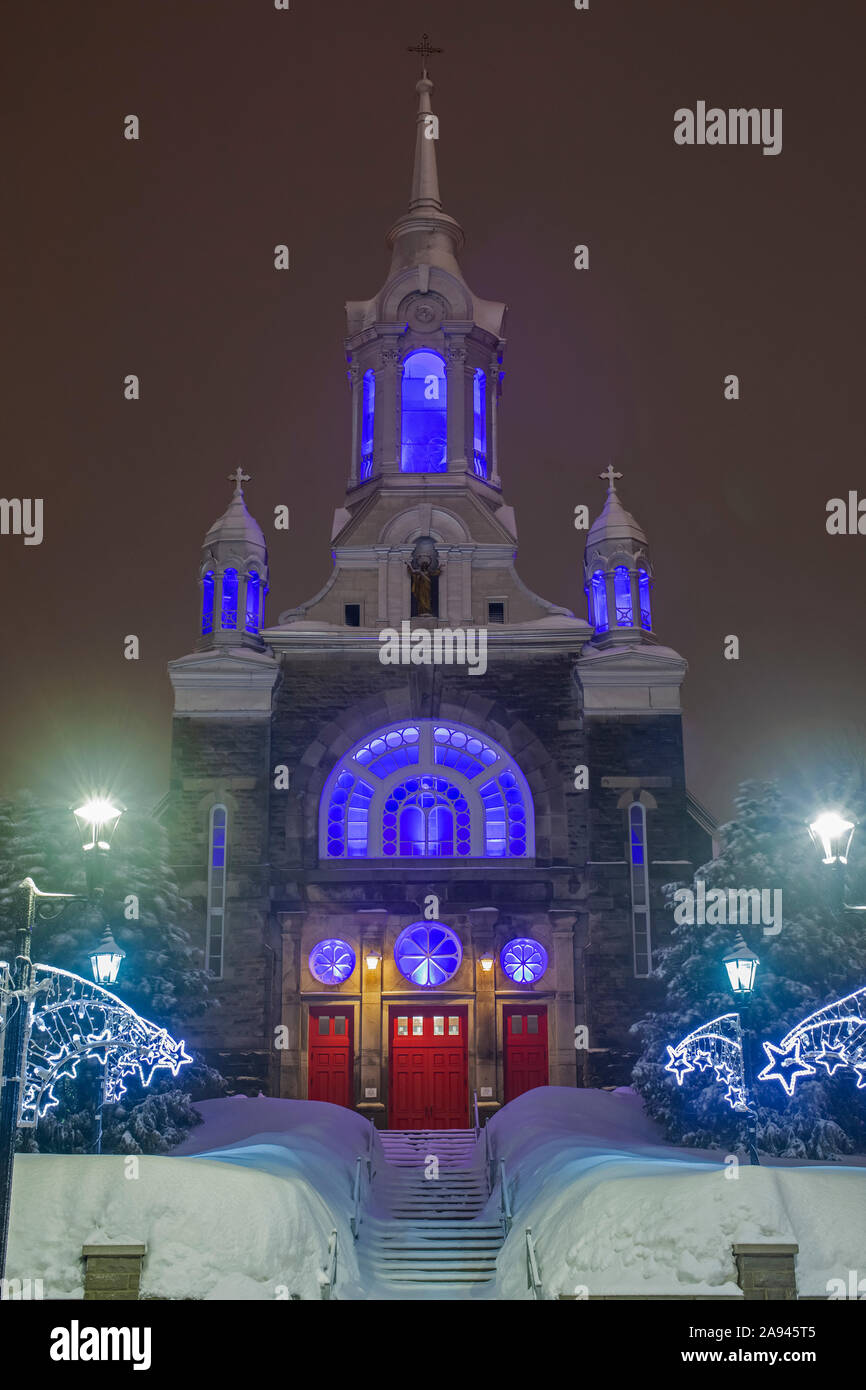 Chiesa cattolica illuminata a Christmastime con le rive di neve; Mont Saint Saveur, Quebec, Canada Foto Stock