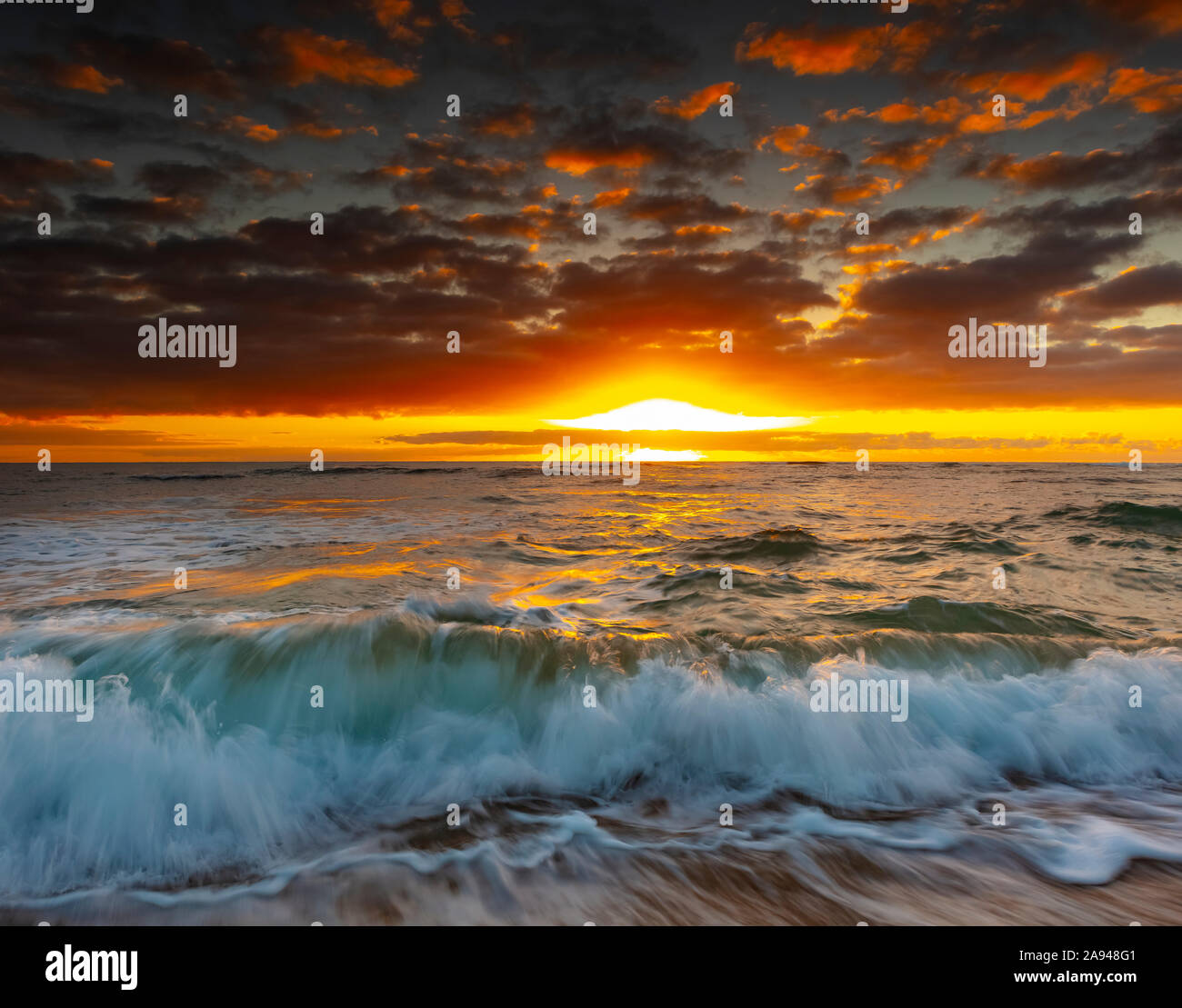 Un'alba luminosa e dorata sulla spiaggia e sull'oceano; Kauai, Hawaii, Stati Uniti d'America Foto Stock