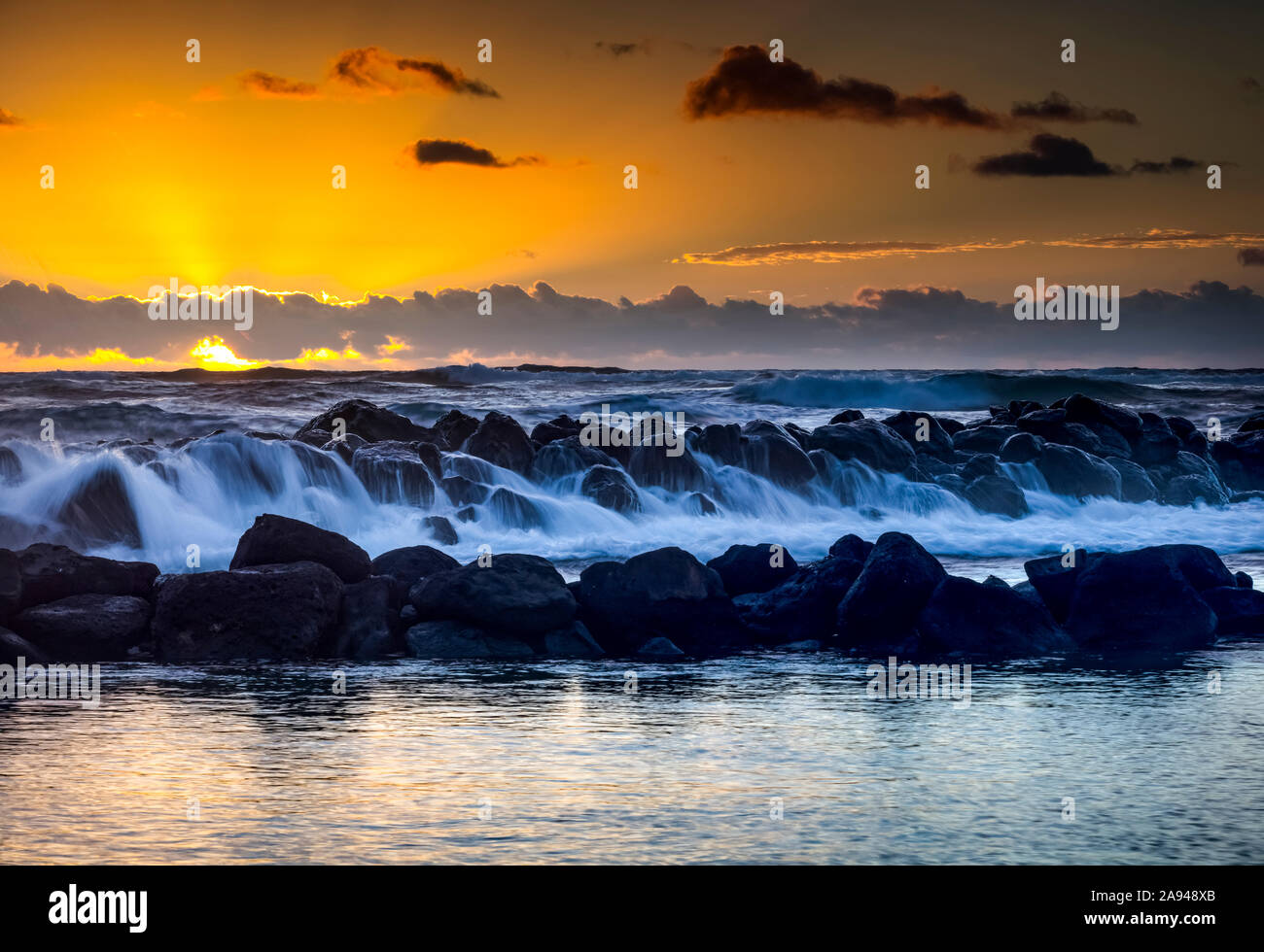 Aurea alba su Lydgate Park e l'oceano dalla costa di Kauai con una scogliera frangiflutti; Kapaa, Kauai, Hawaii, Stati Uniti d'America Foto Stock