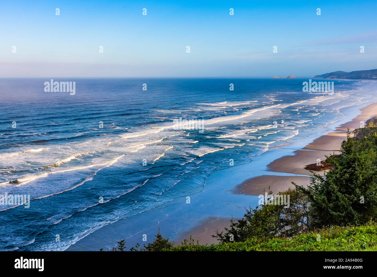 Vista lungo la costa dell'Oregon e l'oceano Pacifico blu contro un cielo blu; Oregon, Stati Uniti d'America Foto Stock
