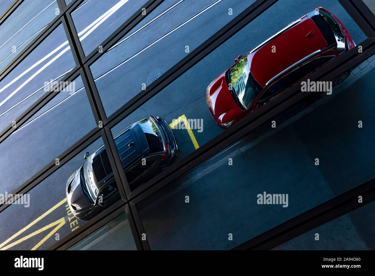 Auto parcheggiate all'esterno di un edificio visto attraverso il muro di vetro; Basilea, Basilea Città, Svizzera Foto Stock