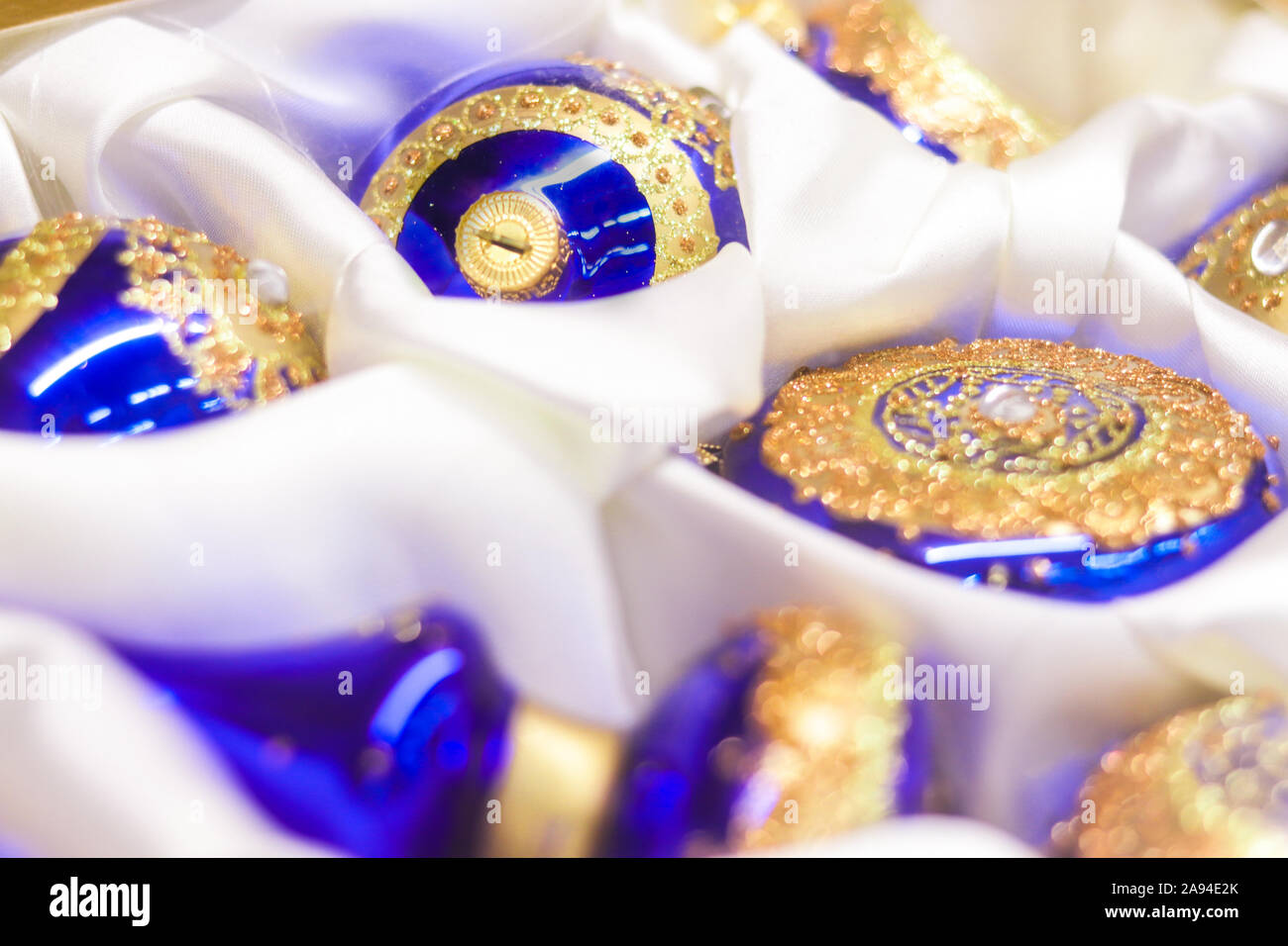 Albero di natale palle blu e con ornamenti dorati e strass su una bianca tela in seta - closeup soft focus sullo sfondo Foto Stock