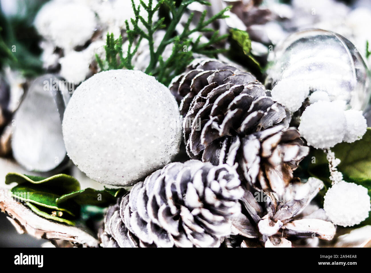 Close up soft focus scheda sfondo per vacanze auguri. Le decorazioni di Natale coni di pino bianco e argento sfere Foto Stock