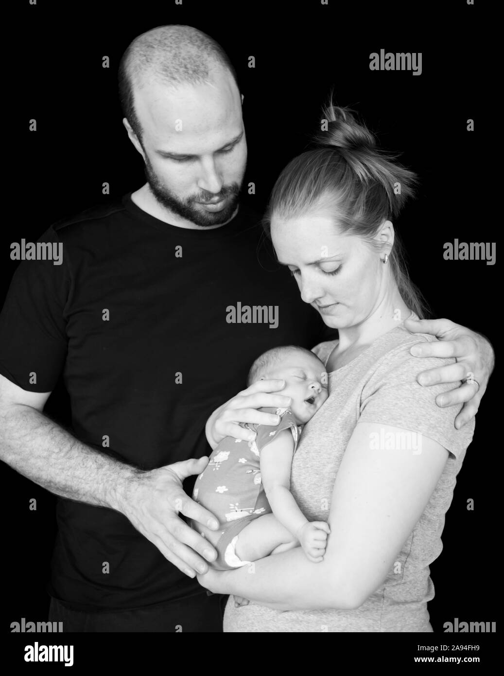 Ritratto del neonato che dorme nelle braccia della madre con il padre in piedi in un abbraccio; Vancouver, British Columbia, Canada Foto Stock