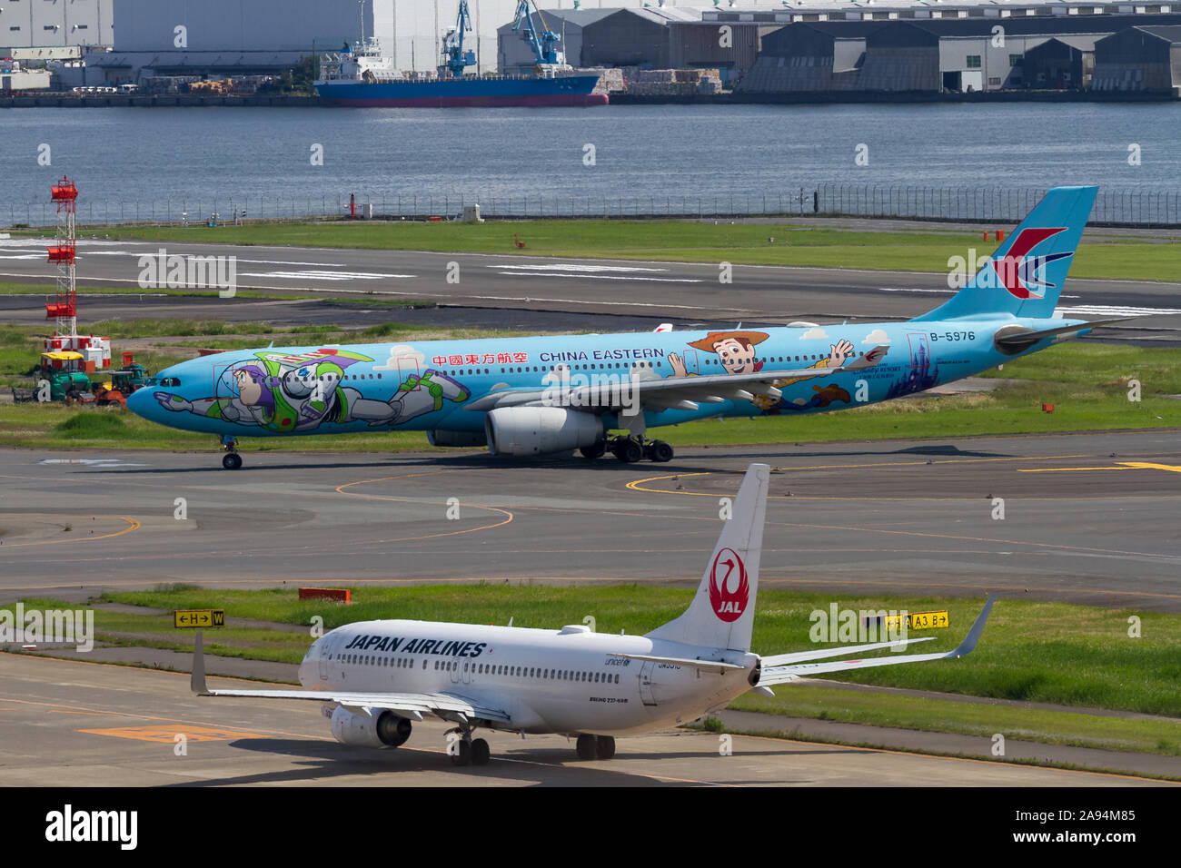 Una China Eastern Airlines A330-343 decorata con personaggi Disney Toy Story passa davanti a un JAL 737-800 all'aeroporto Haneda di tokyo, Giappone Foto Stock