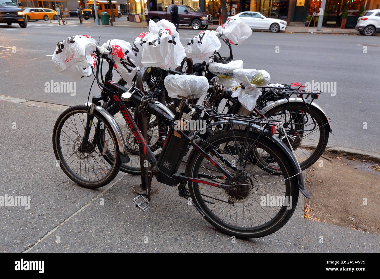 I Love NY sacchetti di plastica avvolto intorno ad un manubrio di bicicletta e sedi di biciclette elettriche utilizzate dal personale addetto alle consegne Foto Stock
