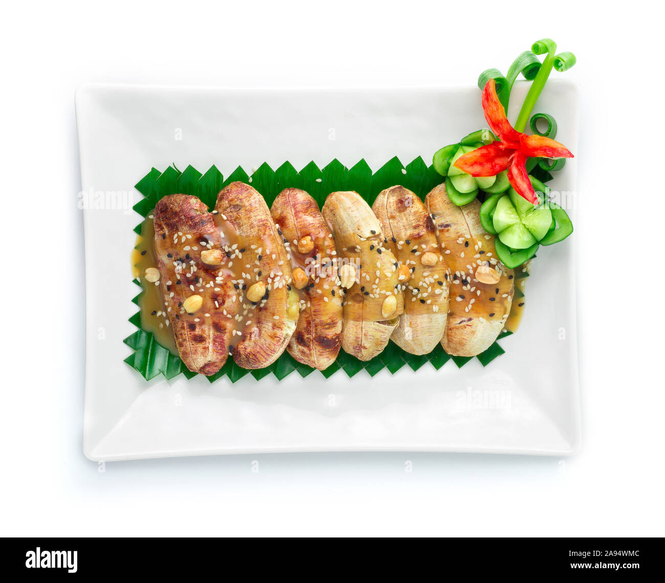 Banane alla griglia con i dolci di zucchero di canna e latte di cocco Salsa e rabboccato con sesamo e arachidi dessert Thai decorare con scolpito il cetriolo ,chili vegetabl Foto Stock