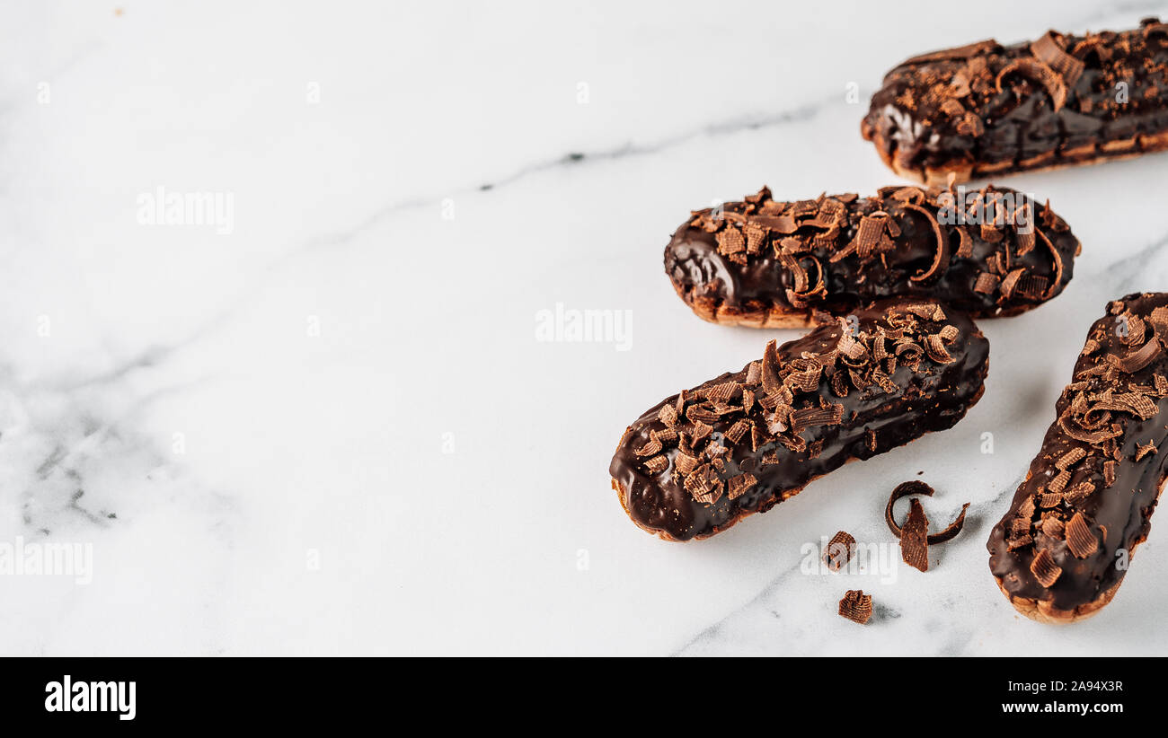 Set di eclairs fatti in casa con cioccolato bianco su sfondo marmo. Vista ravvicinata della deliziosa profitroles sani con glassa di cioccolato. Copia spazio per il testo o il design. Banner Foto Stock