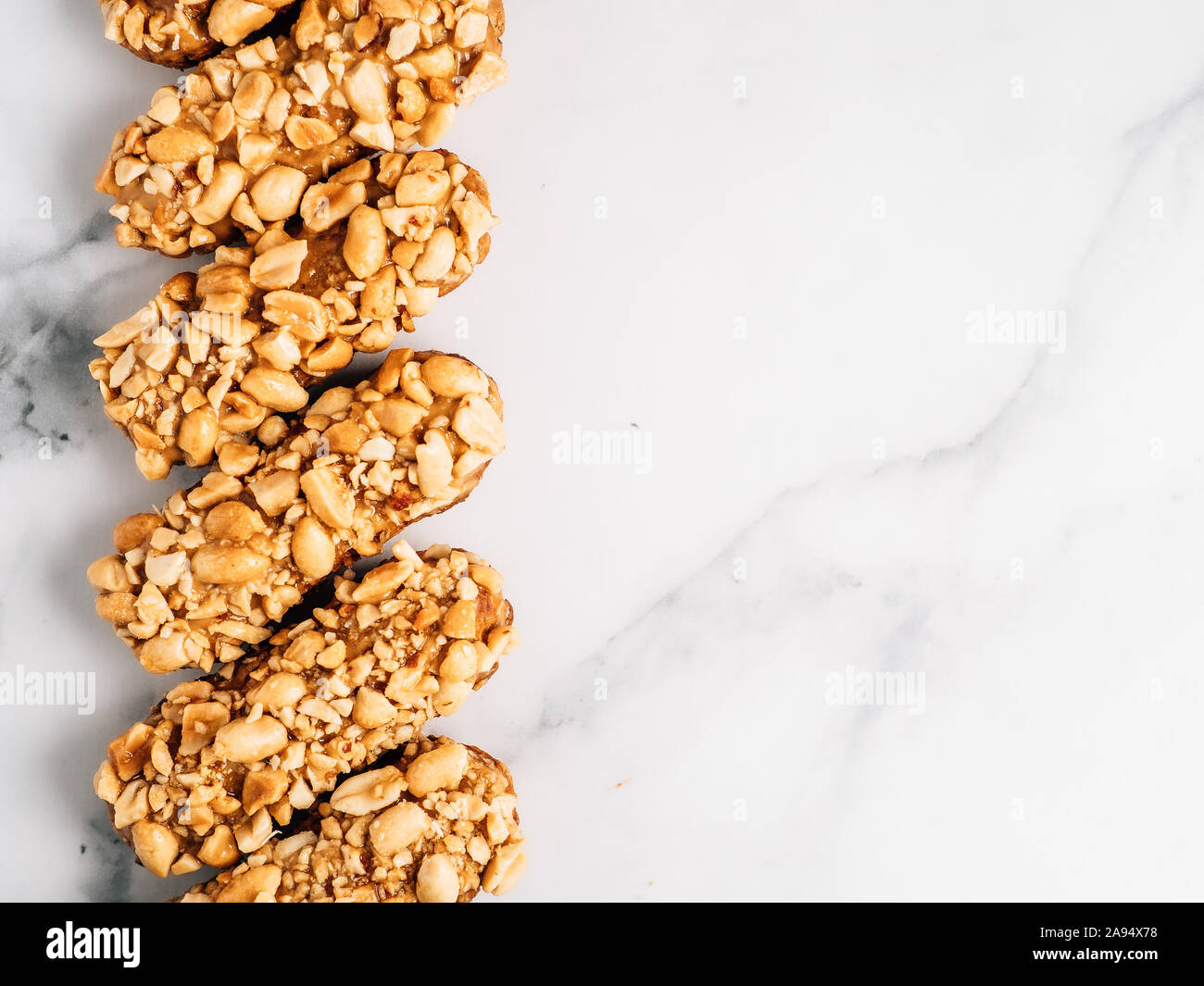 Set di eclairs fatti in casa con decorazioni di arachidi su sfondo marmo. Vista superiore della deliziosa profitroles sano con i dadi. Copia spazio per il testo o il design. Foto Stock