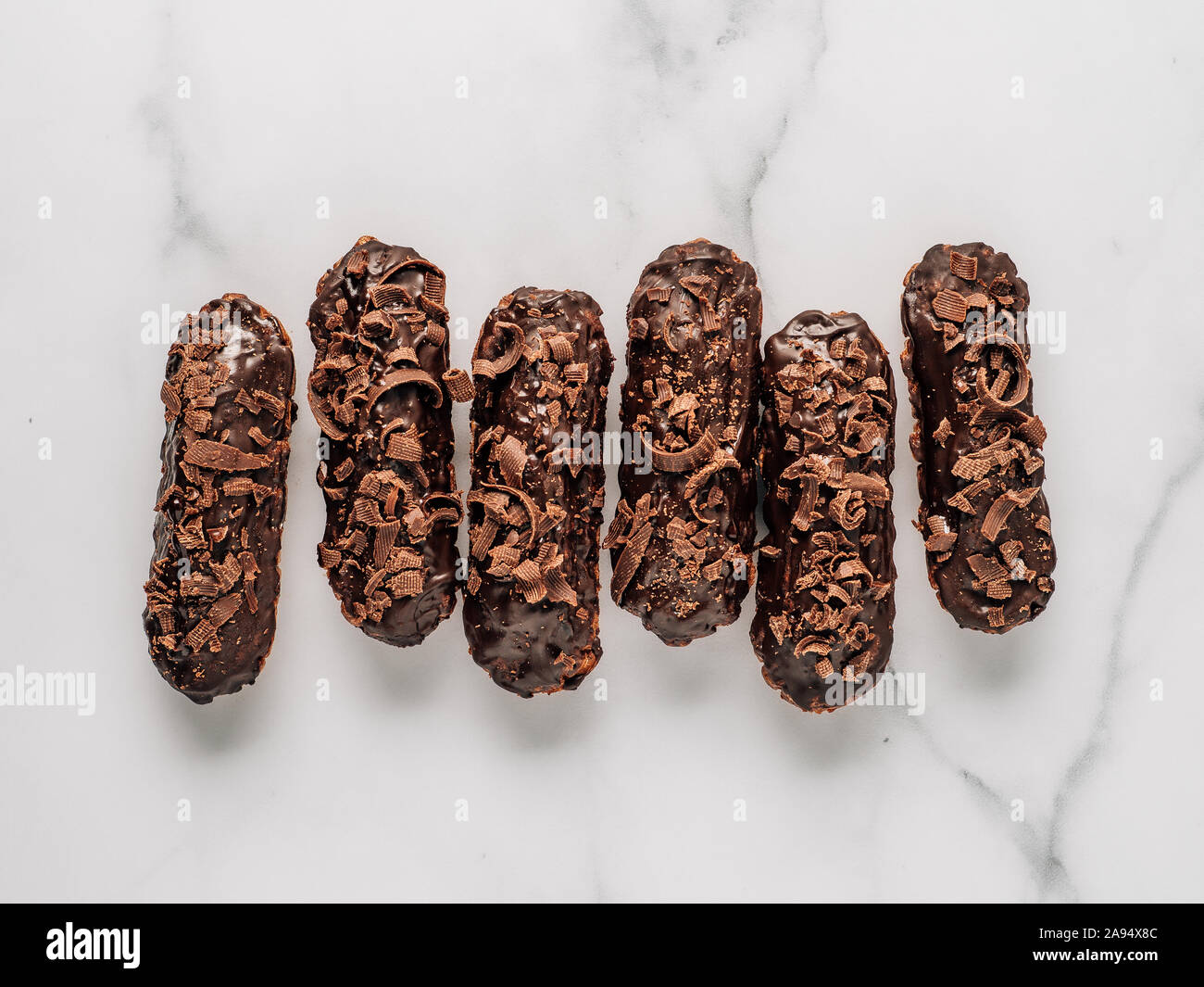 Set di eclairs fatti in casa con cioccolato su sfondo marmo. Vista superiore della deliziosa profitroles sani con glassa di cioccolato. Copia spazio per il testo o per la progettazione Foto Stock