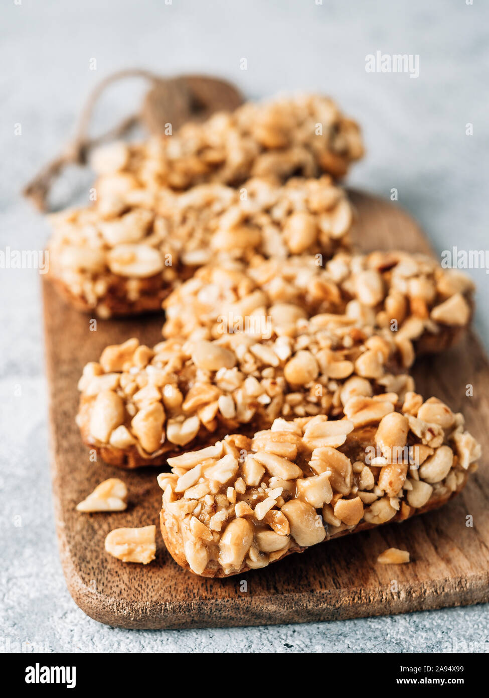 In casa eclairs con arachidi sul bordo di taglio. Vista ravvicinata della deliziosa profitroles sano con i dadi. Copia spazio per il testo o il design. Verticale. Foto Stock