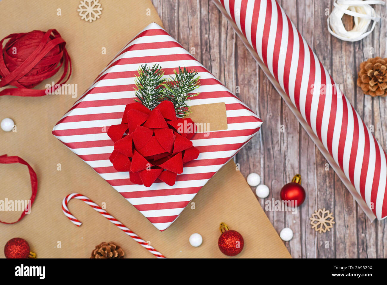 Piatto concetto di laici per il Natale confezione regalo con bella rossa e bianca a strisce confezione regalo con un grande arco rosso, carta da imballaggio, nastri e la decorazione l Foto Stock