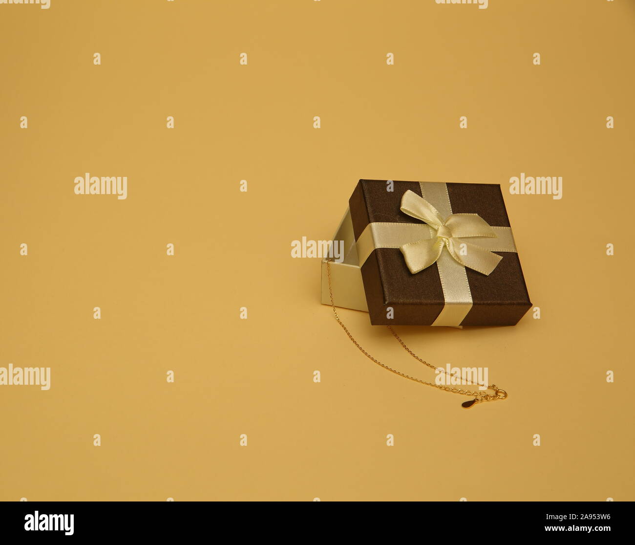 Confezione regalo decorativa aperta a metà con catena dorata all'interno, spazio copia sfondo pastello Foto Stock